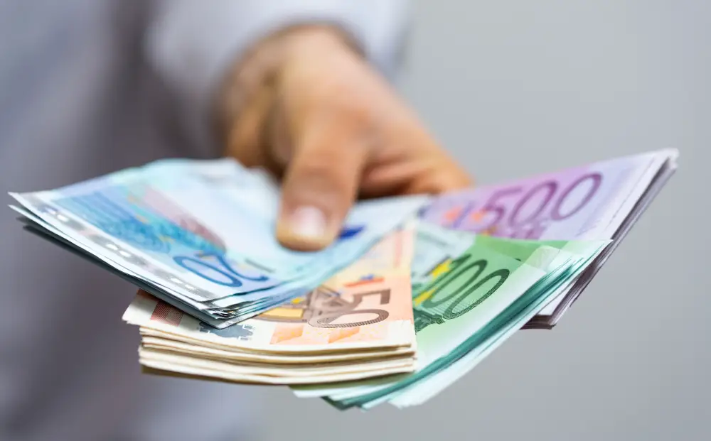 Mano entregando billetes de euro tras vender oro